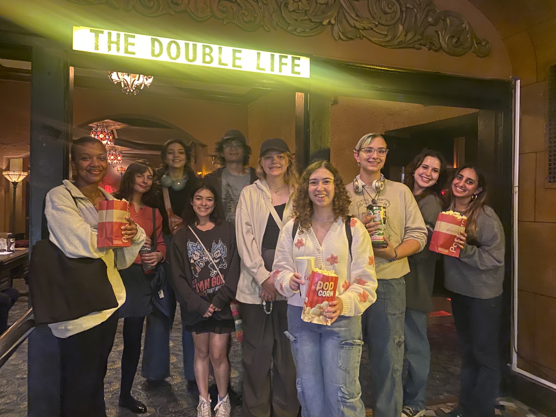 Group of students holding popcorn, posing outside a theater showing The Double Life at the Music Box.